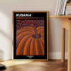 Orange pumpkin covered in black polka dots in Yayoi Kusama's style - beside a round wooden side table with books