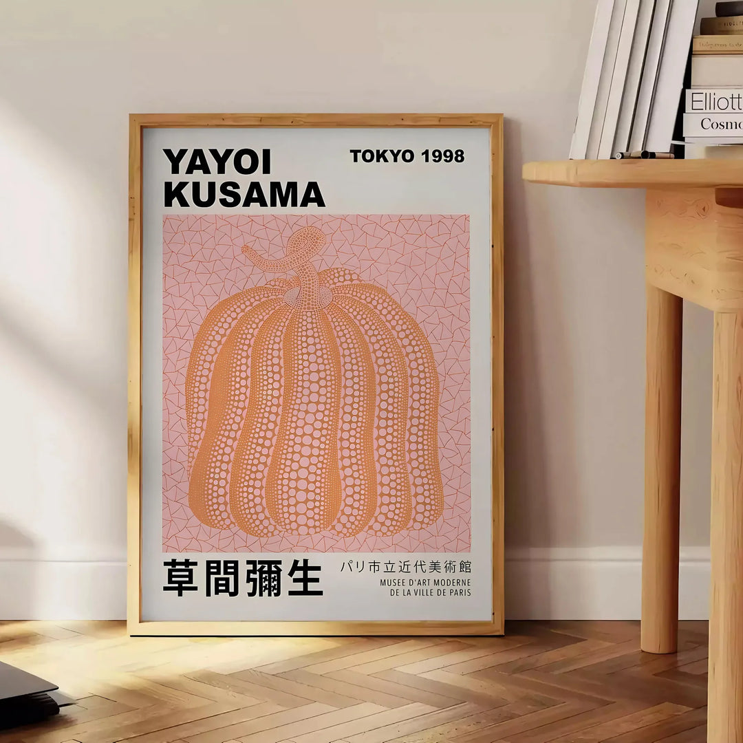 A pumpkin pattern in Yayoi Kusama's signature polka dot style with black and brown tones - beside a round wooden side table with books