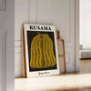A pumpkin with polka dots in Yayoi Kusama's signature style, orange and black colors - leaning on a herringbone floor against a white panelled wall