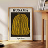 A pumpkin with polka dots in Yayoi Kusama's signature style, orange and black colors - beside a round wooden side table with books
