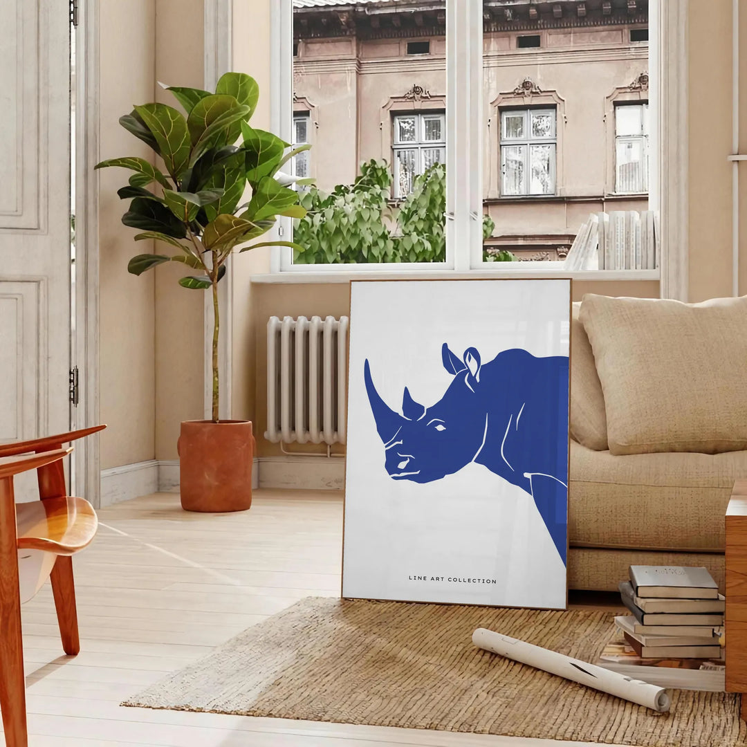 A rhinoceros standing in a natural habitat with blue and black tones - in a Parisian living room with a sofa and a fig plant