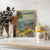 Travel poster depicting Sanremo, Italy, in soft gray and green tones - styled on a counter with eucalyptus and a bowl of lemons