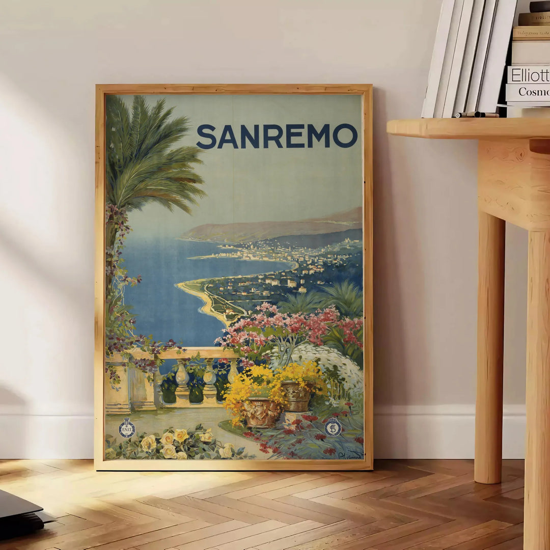 Travel poster depicting Sanremo, Italy, in soft gray and green tones - beside a round wooden side table with books