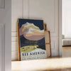 A vintage travel poster depicting serene landscapes of America in green and blue hues - leaning on a herringbone floor against a white panelled wall
