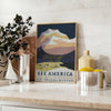 A vintage travel poster depicting serene landscapes of America in green and blue hues - styled on a counter with eucalyptus and a bowl of lemons