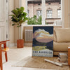 A vintage travel poster depicting serene landscapes of America in green and blue hues - in a Parisian living room with a sofa and a fig plant