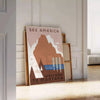 Vintage-style travel poster featuring the USA in muted gray and brown tones - leaning on a herringbone floor against a white panelled wall