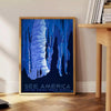 A vintage-style travel poster featuring iconic American landscapes in blue and black tones - beside a round wooden side table with books