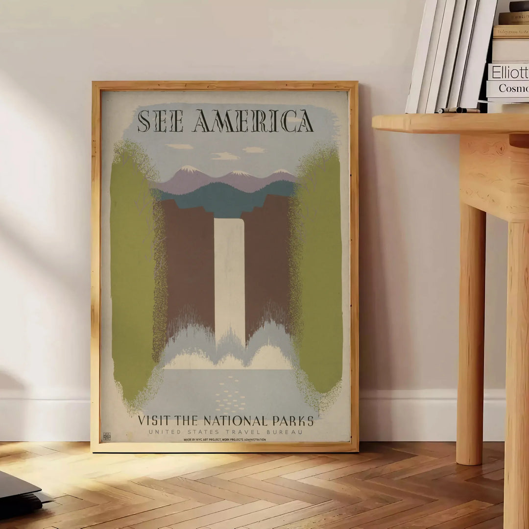 A vintage travel poster featuring the text 'See America' with green and gray landscapes. - beside a round wooden side table with books