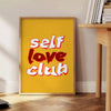 Abstract design featuring the phrase 'Self Love Club' in bold typography with warm orange and red tones - beside a round wooden side table with books