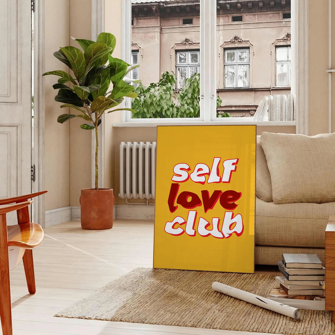 Abstract design featuring the phrase 'Self Love Club' in bold typography with warm orange and red tones - in a Parisian living room with a sofa and a fig plant