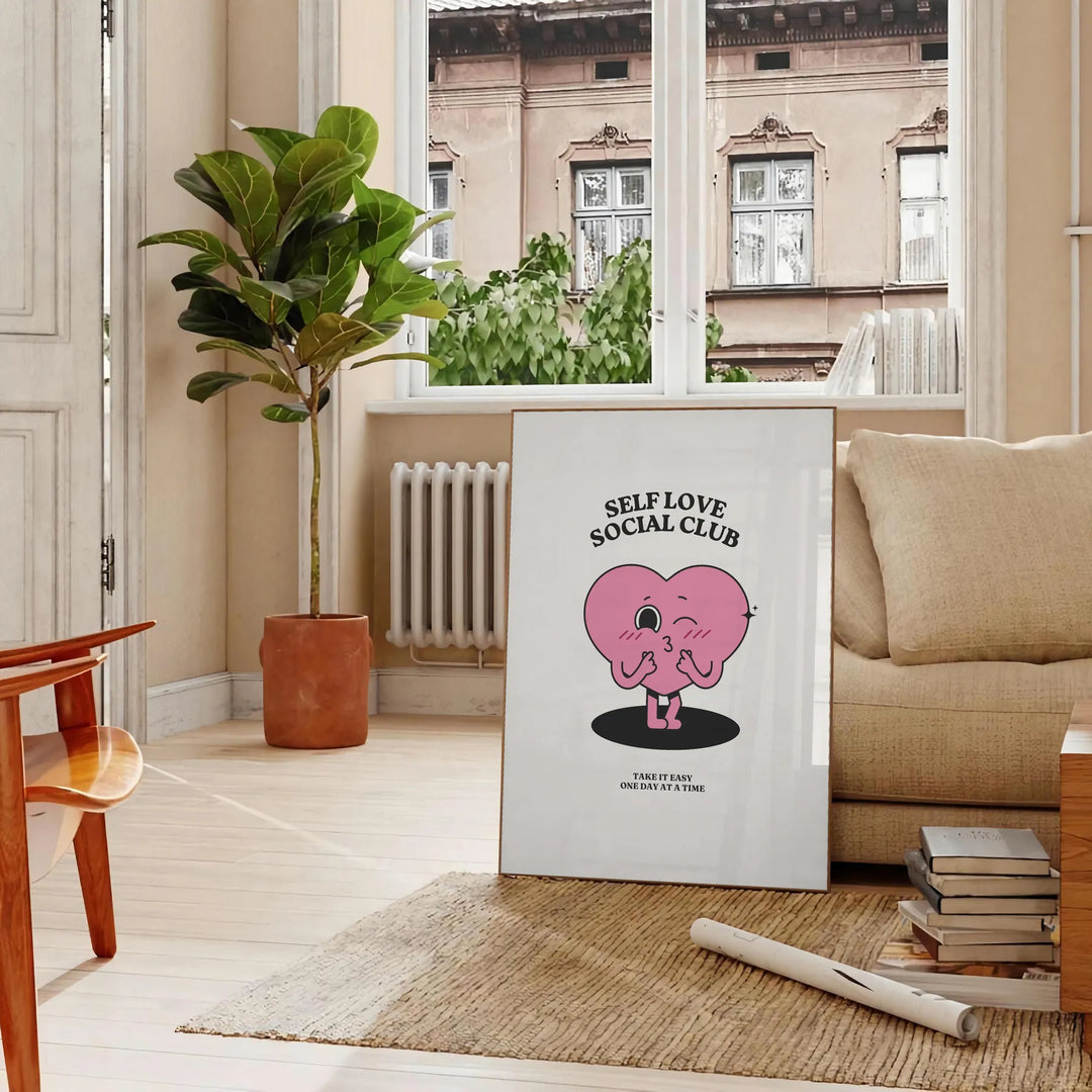 Minimalist poster featuring the phrase 'Self Love Social Club' in bold typography against a gray background - in a Parisian living room with a sofa and a fig plant
