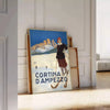 A vintage-style ski travel poster featuring snowy mountains and a bright blue sky - leaning on a herringbone floor against a white panelled wall