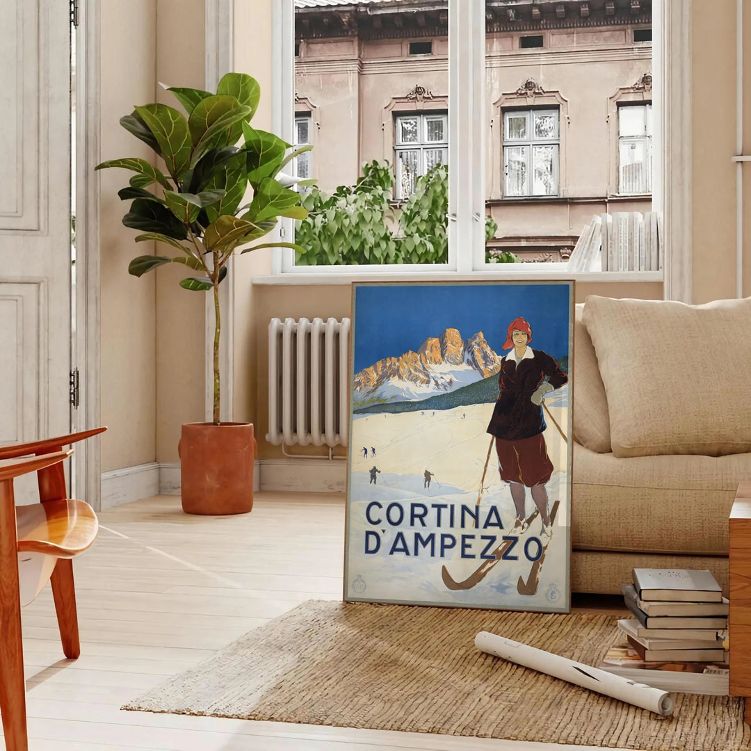 A vintage-style ski travel poster featuring snowy mountains and a bright blue sky - in a Parisian living room with a sofa and a fig plant