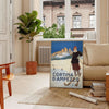 A vintage-style ski travel poster featuring snowy mountains and a bright blue sky - in a Parisian living room with a sofa and a fig plant