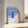 A ski scene with snowy slopes and blue skies - leaning on a herringbone floor against a white panelled wall