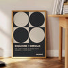 Abstract composition of squares and circles in black and brown tones - beside a round wooden side table with books