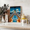 Poster showing a surreal swimming Titanic illustration in blue and green - styled on a counter with eucalyptus and a bowl of lemons