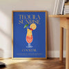 A colorful illustration of a Tequila Sunrise cocktail with orange and yellow hues. - beside a round wooden side table with books