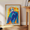 Maximalist poster featuring bold purple and orange hues with abstract shapes - beside a round wooden side table with books
