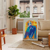 Maximalist poster featuring bold purple and orange hues with abstract shapes - in a Parisian living room with a sofa and a fig plant