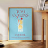 Illustration of a Tom Collins cocktail in a glass with lemon and cherry, yellow and blue colors - beside a round wooden side table with books