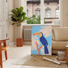 A colorful toucan perched on a branch with bright orange and blue feathers - in a Parisian living room with a sofa and a fig plant