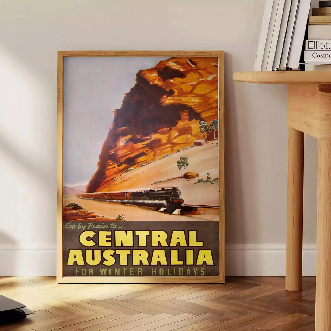 Illustration of a train traveling through lush Australian landscapes in green and blue tones - beside a round wooden side table with books