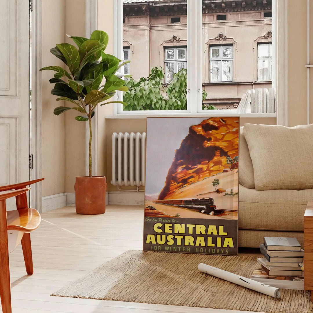 Illustration of a train traveling through lush Australian landscapes in green and blue tones - in a Parisian living room with a sofa and a fig plant