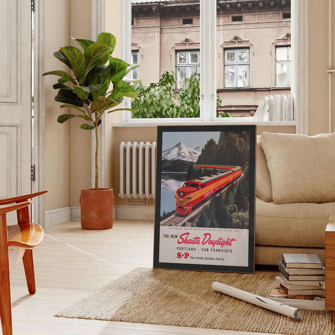 Vintage travel poster featuring a train traveling from Portland to San Francisco in orange and green tones - in a Parisian living room with a sofa and a fig plant