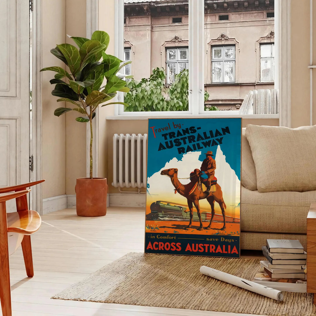 Retro travel poster featuring the Trans Australian Railway with green and blue tones - in a Parisian living room with a sofa and a fig plant