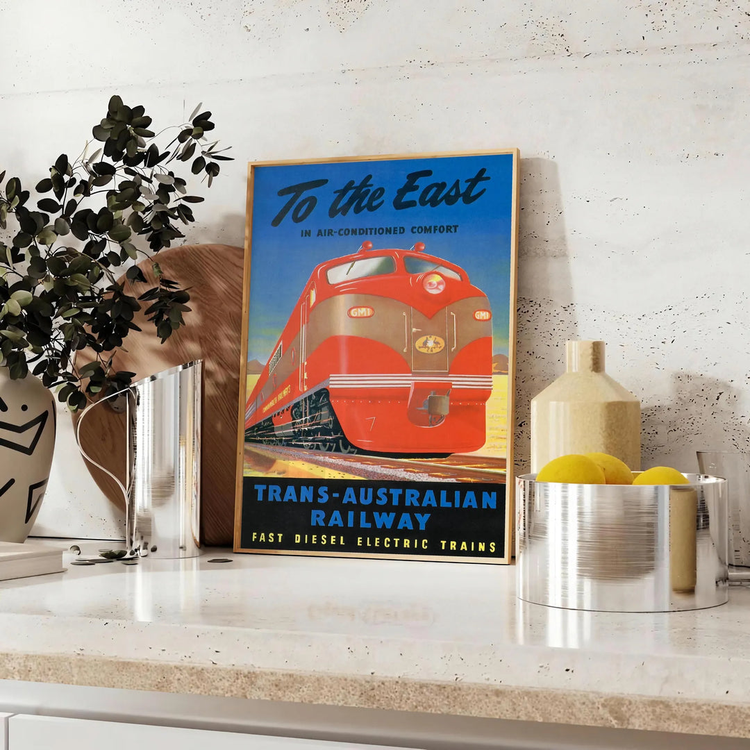 Vintage travel poster featuring the Trans Australian Railway in green and black hues - styled on a counter with eucalyptus and a bowl of lemons