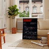 A humorous travel poster featuring a cartoonish traveler with a distressed expression, predominantly black and red colors. - in a Parisian living room with a sofa and a fig plant