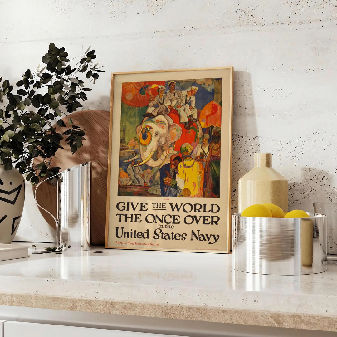 United States Navy travel poster featuring a ship in blue and red tones - styled on a counter with eucalyptus and a bowl of lemons