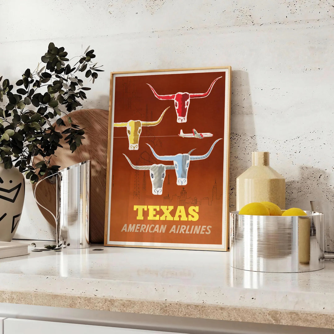 American Airlines travel poster featuring Texas with bold orange and yellow colors - styled on a counter with eucalyptus and a bowl of lemons