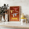 American Airlines travel poster featuring Texas with bold orange and yellow colors - styled on a counter with eucalyptus and a bowl of lemons