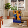 A travel poster featuring a serene landscape in green and blue hues - in a Parisian living room with a sofa and a fig plant
