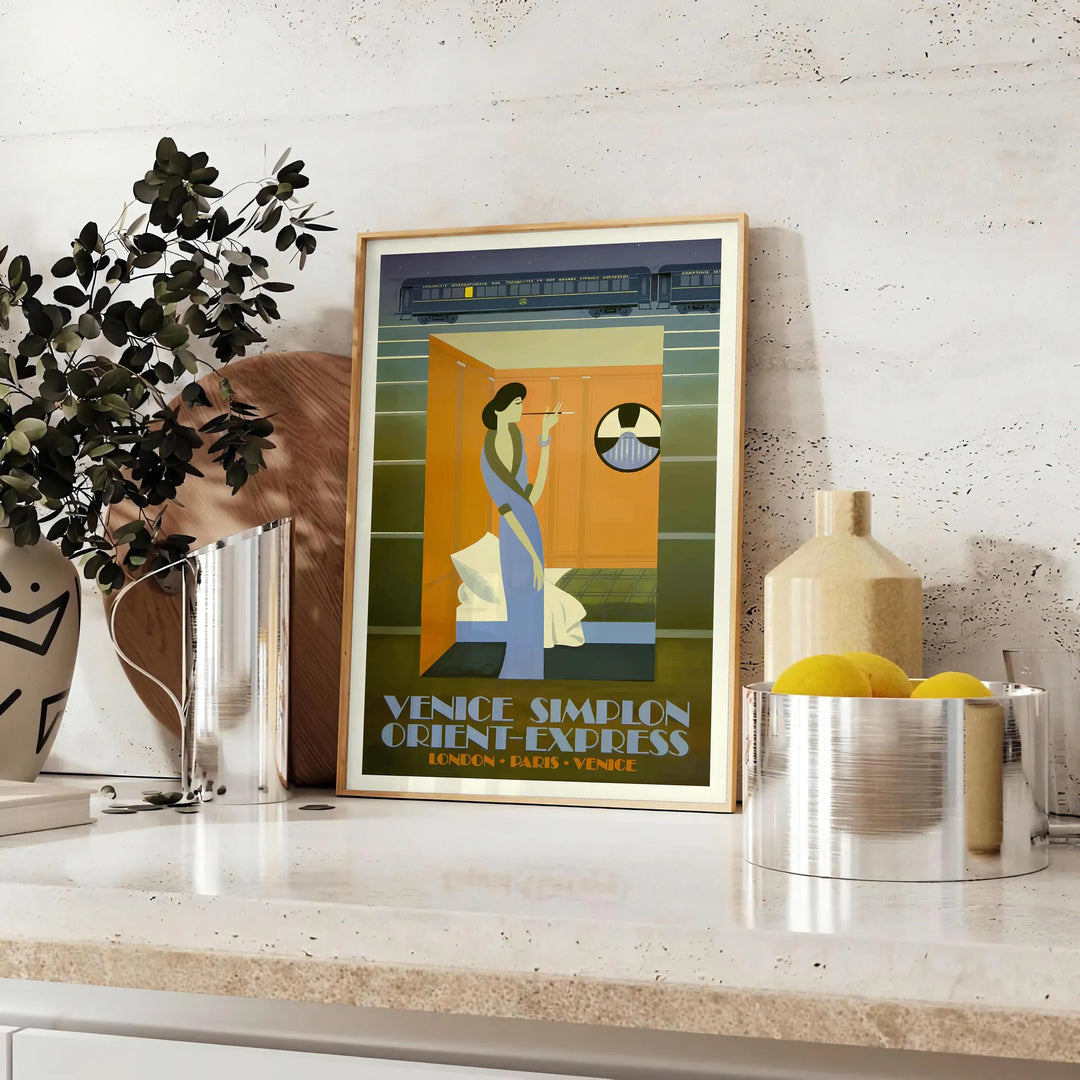 Vintage travel poster featuring the Venice Simplon train in rich browns and greens - styled on a counter with eucalyptus and a bowl of lemons