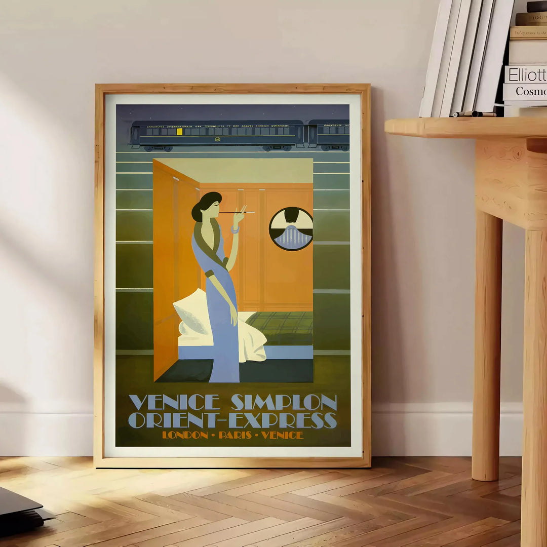 Vintage travel poster featuring the Venice Simplon train in rich browns and greens - beside a round wooden side table with books