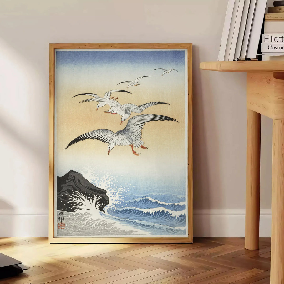 A vintage Japanese poster featuring a bird in green and orange hues - beside a round wooden side table with books