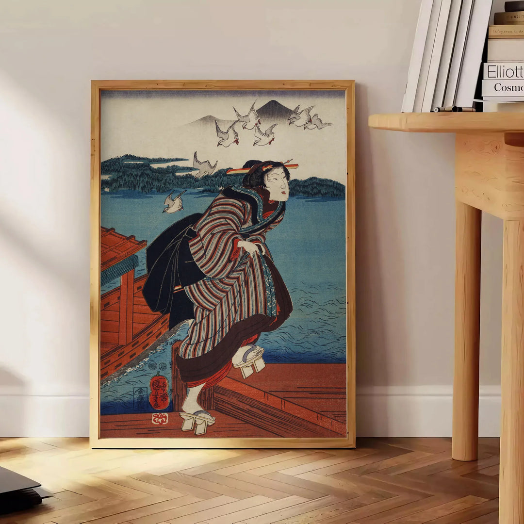 En vintage japansk konsttryck med traditionella motiv i dämpade färger - bredvid ett runt sidobord i trä med böcker