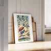 Une affiche de voyage vintage avec un chariot volant sur fond gris-bleu - posée sur un parquet à chevrons contre un mur à moulures