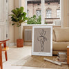 A bohemian-style portrait of a woman with earthy tones and floral elements - in a Parisian living room with a sofa and a fig plant