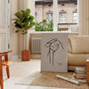 A bohemian woman with flowing hair surrounded by abstract shapes and earthy tones - in a Parisian living room with a sofa and a fig plant