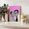 A pink and purple abstract artwork featuring a woman and a man - styled on a counter with eucalyptus and a bowl of lemons