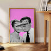 A pink and purple abstract artwork featuring a woman and a man - beside a round wooden side table with books