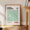 Abstract polka dot patterns in gray and blue by Yayoi Kusama - beside a round wooden side table with books