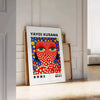 Motifs colorés de pois en orange et bleu par Yayoi Kusama - posée sur un parquet à chevrons contre un mur à moulures