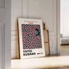 Abstract polka dot pattern in green and orange by Yayoi Kusama - leaning on a herringbone floor against a white panelled wall