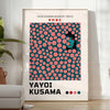 Abstract polka dot pattern in green and orange by Yayoi Kusama - in a bright minimalist room with a plant and an armchair
